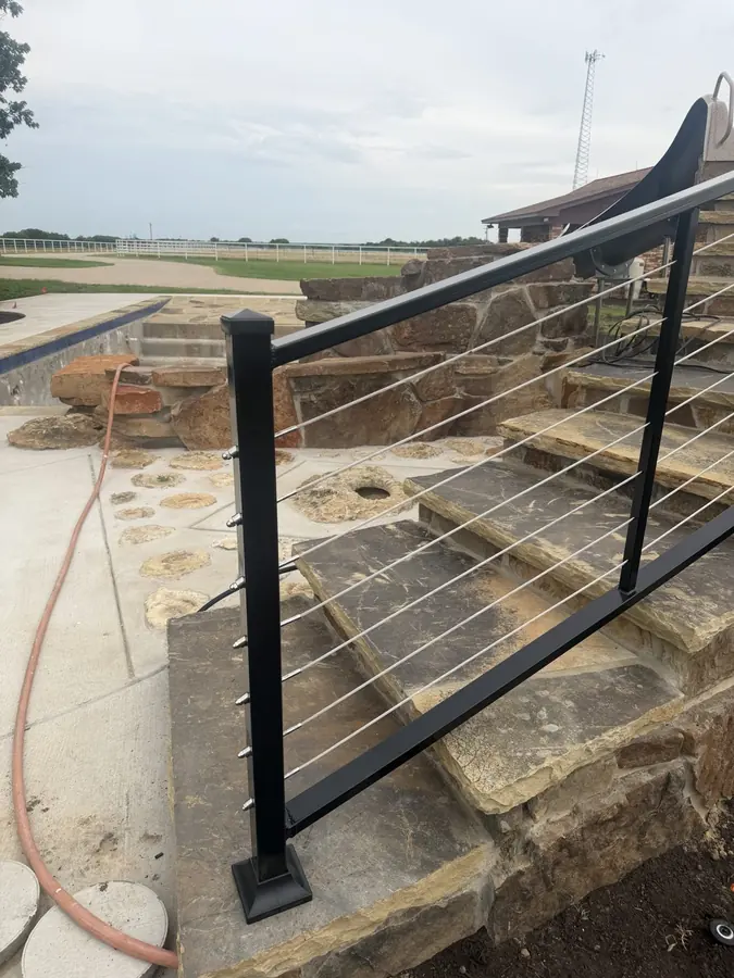 Powder-coated steel and cable railing along a stone pool deck