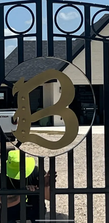 Iron driveway gate with a custom gold monogram medallion